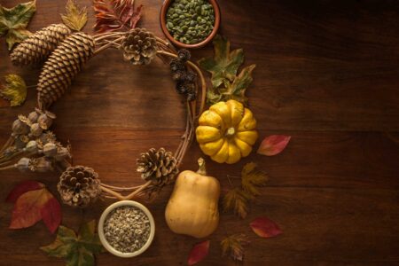 Autumn harvest flat lay with pine cones, acorns, poppies, autumn leaves, squashes, gourds, pumpkin & sunflower seeds